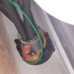 under-sink view of water line connection and grounding wire.