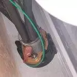 under-sink view of water line connection and grounding wire.